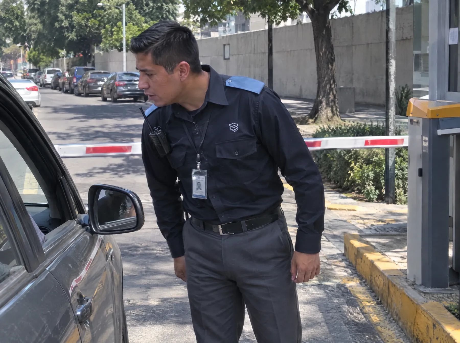 Guardia en la pluma de acceso al estacionamiento de un edificio pregunta el destino a un conductor